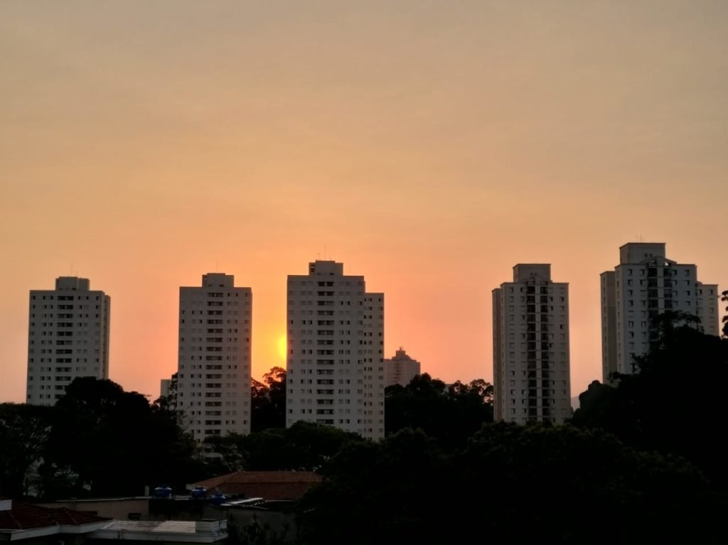 Sol se pondo atrás dos prédios de São Paulo. O céu fica com tom em laranja.