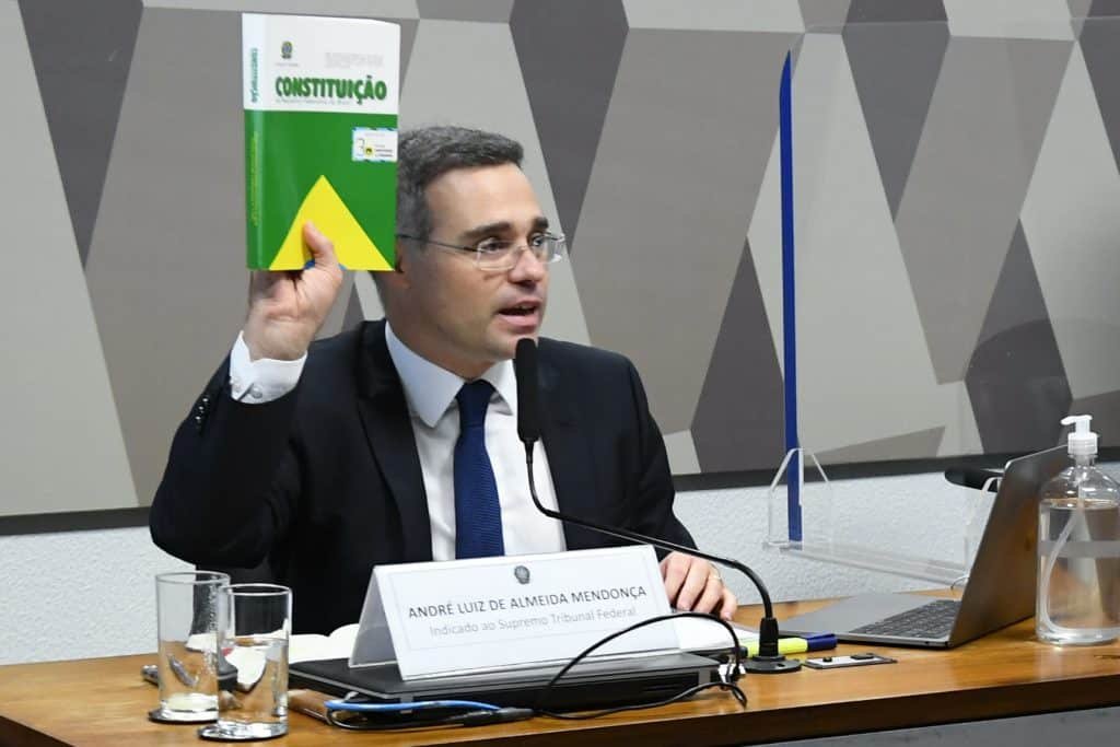 André Mendonça segura a constituição brasileira com a mão direita enquanto fala aos senadores, durante sabatina na comissão de constituição e justiça do Senado Federal.