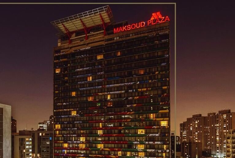 Imagem mostra prédio onde funcionava o hotel Maksoud Plaza, ao cair da noite, com luzes de alguns quartos acesas. Ao fundo, prédios menores.