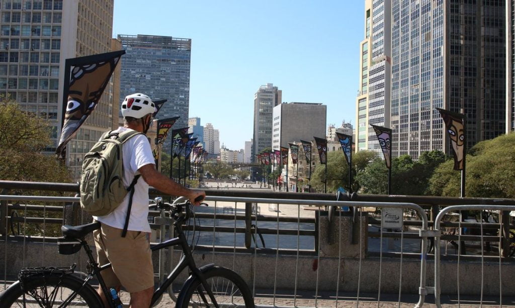 Ciclista, com mochila nas costas, observa o vale do anhangabaú do alto do viaduto do Chá.