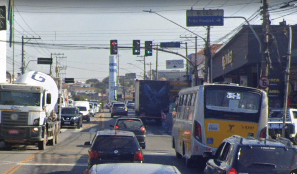 Cruzamento na avenida Marechal Tito, na zona leste, com caminhões, ônibus e carros passando. No alto há uma placa indicando a uinidade do Ceu "Três Pontes",