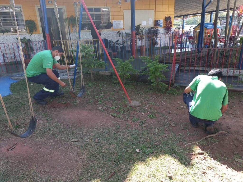 Agentes da prefeitura coletam amostras de terra em local usado por alunos para brincar em escola municipal.