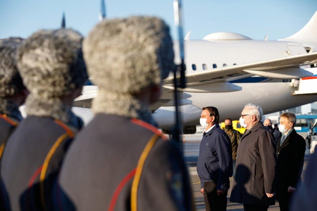 Jair Bolsonaro é recepcionado em Moscou diante da aeronave oficial. Honras militares marcaram a chegada do presidente, que usava máscara de proteção respiratória.