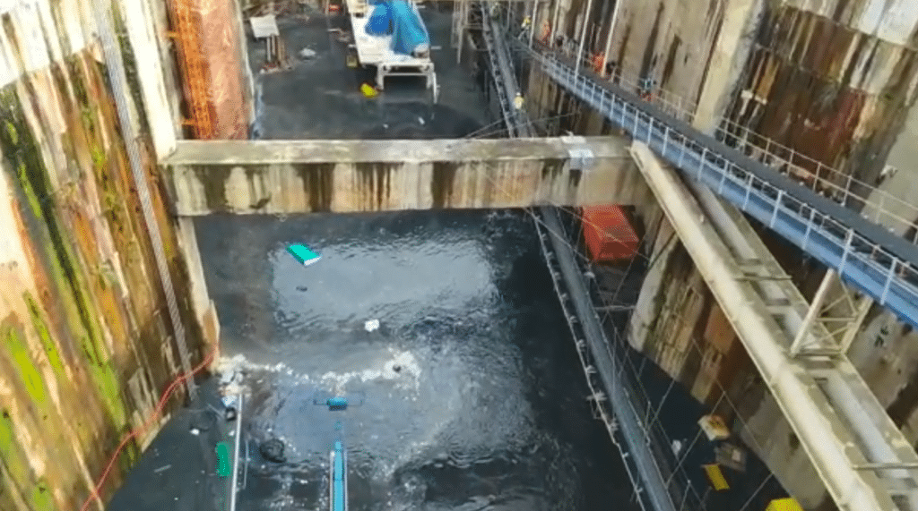 Tunel do metro tomado por água suja, de cor escura.