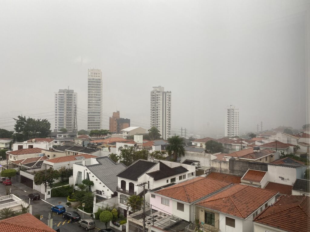 Foto mostra telhados de casas e predios desaparecendo no meio da chuva que se aproximava.