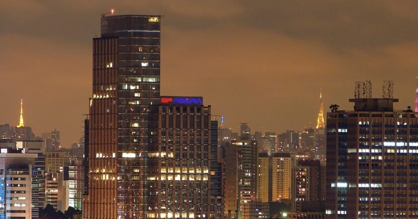 Foto panoramica mostra a cidade de sao paulo a noite. é possível ver o topo dos prédios e torres de transmissão sobre os prédios.