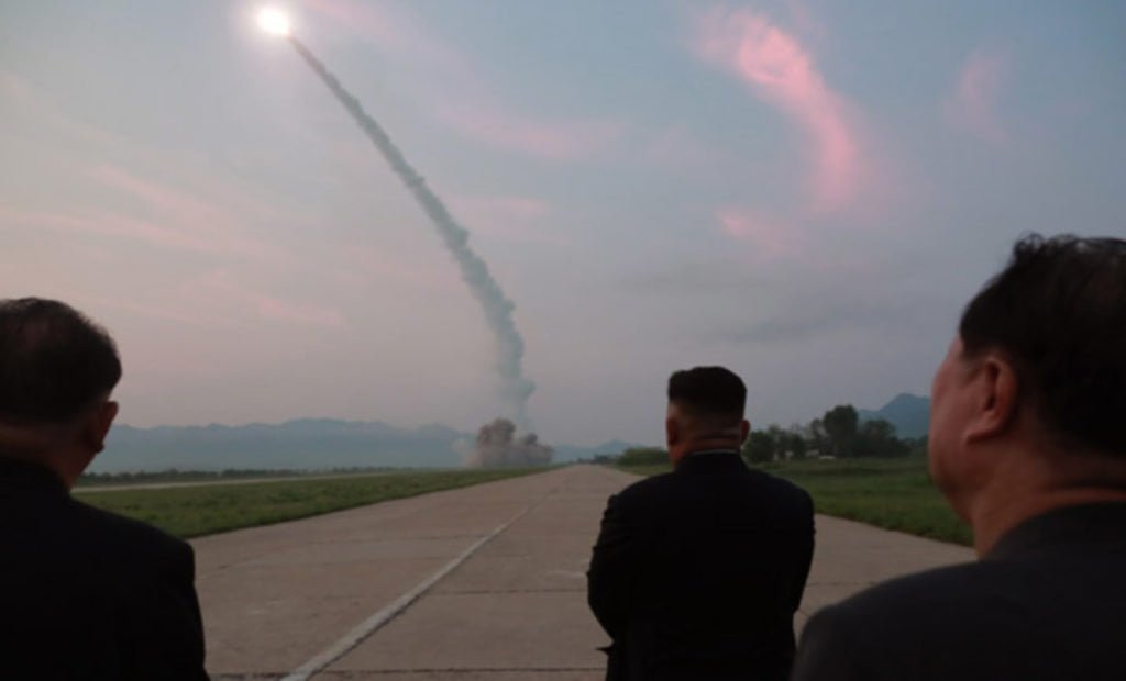 Kim Jong Un e outros membros do governo observam míssel lançado.