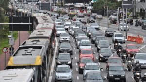 Imagem do alto mostra trânsito congestionado em avenida com várias faixas de carros. No canto esquerdo aparecem ônibus enfileirados.