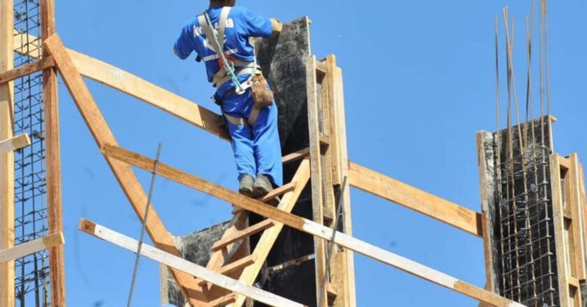 Operário trabalha no alto de uma obra fazendo amarrações nas estruturas em construção
