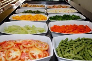 Pratos organizados lado a lado com legumes e saladas.