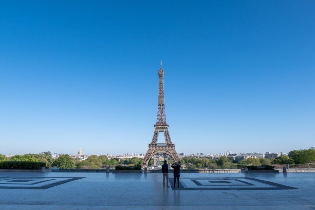Torre Eiffel, em Paris, vista à distância. Perto da torre, pessoas aparecem.