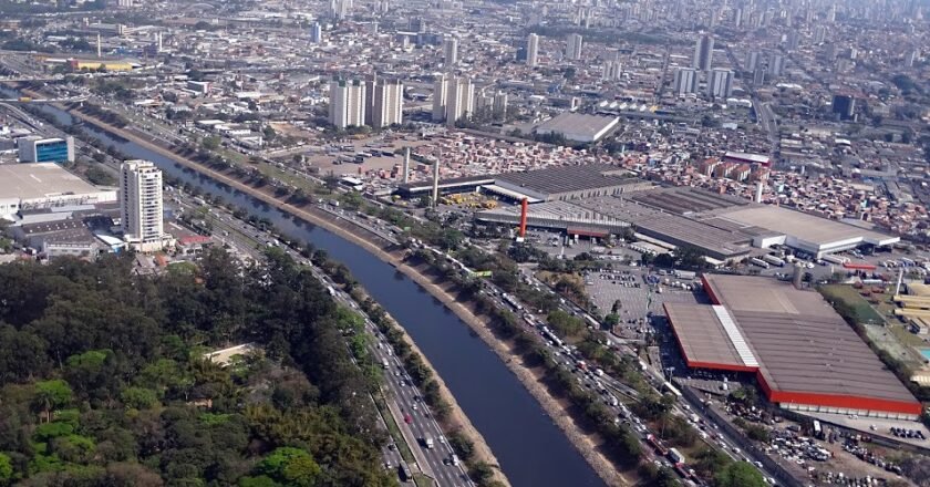 Imagem mostra o rio tietê cortando a cidade de São Paulo. Cercado por prédios.