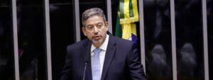 Arthur Lira, homem de cabelos grisalhos, discursa na Câmara dos Deputados. Ao fundo, uma bandeira do Brasil.