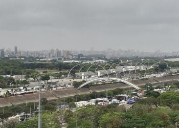 Imagem panorâmica mostra trecho da marginal tiete, em São Paulo, com ceu encoberto por nuvens. É possível ver arcos do sambodromo do anhembi e trânsito congestionado.