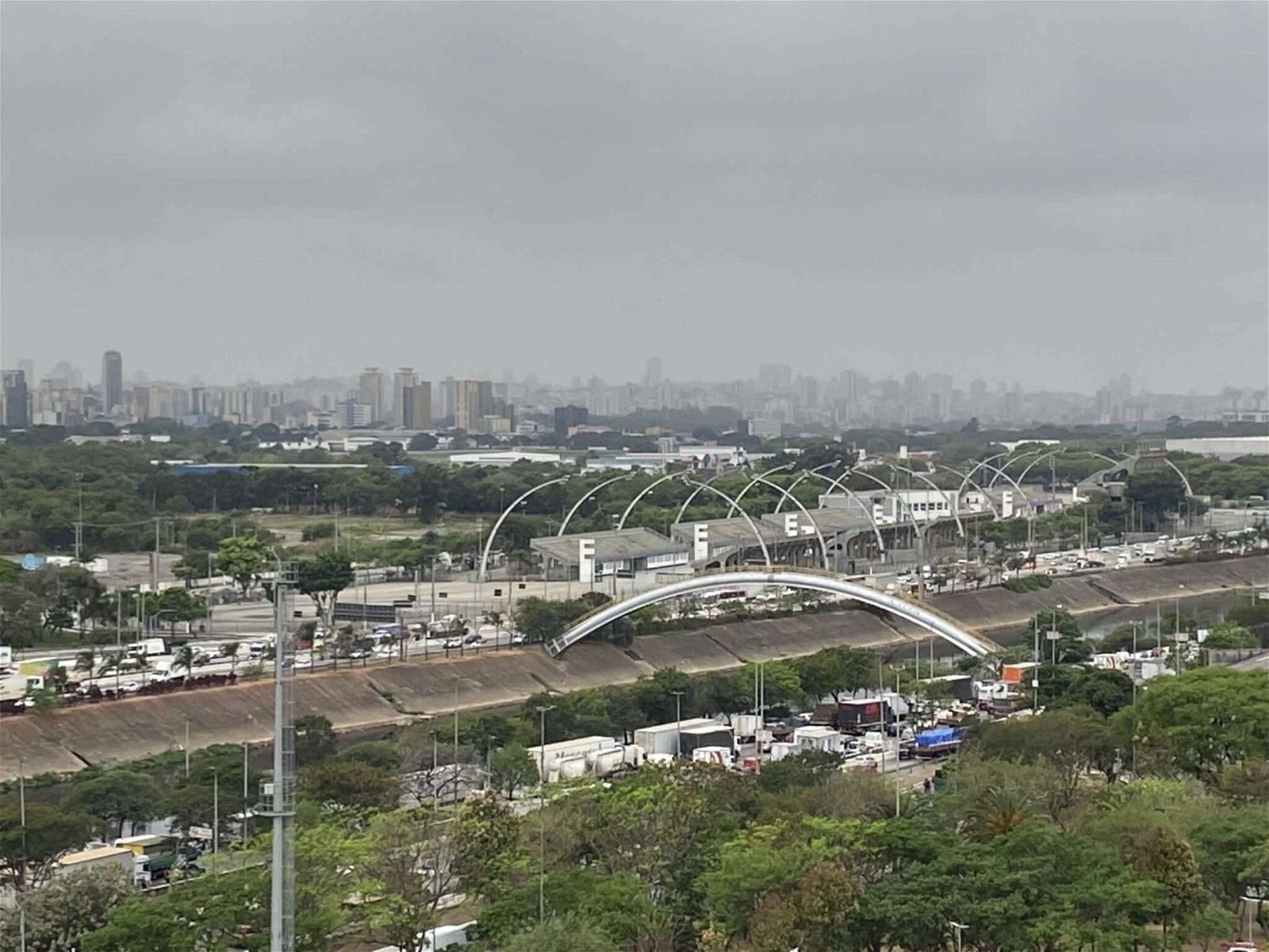 Imagem panorâmica mostra trecho da marginal tiete, em São Paulo, com ceu encoberto por nuvens. É possível ver arcos do sambodromo do anhembi e trânsito congestionado.