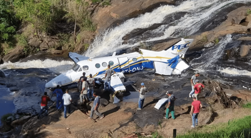 Avião de Marília Mendonça cercado por bombeiros e socorristas sobre uma cachoeira