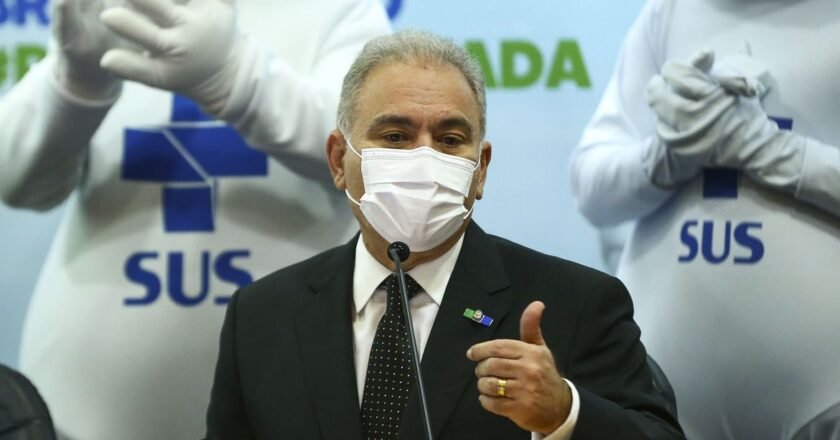 Marcelo Queiroga, ministro da saúde, fala ao microfone diante de duas fotos do zé gotinha. Ze gotinha traz estampado na roupa a marca do Sistema Único de Saúde (sus)