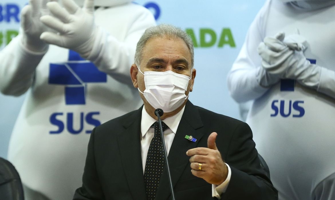 Marcelo Queiroga, ministro da saúde, fala ao microfone diante de duas fotos do zé gotinha. Ze gotinha traz estampado na roupa a marca do Sistema Único de Saúde (sus)