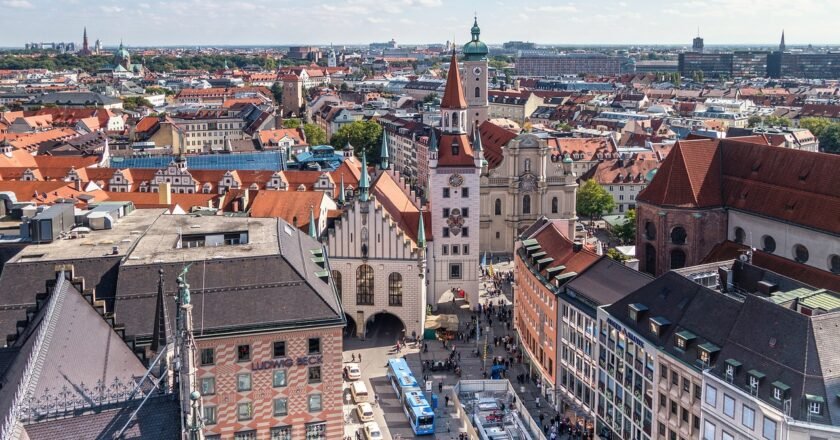 Panorâmica da cidade de Munique, na Alemanha. Mostra prédios e pessoas caminhando na rua.