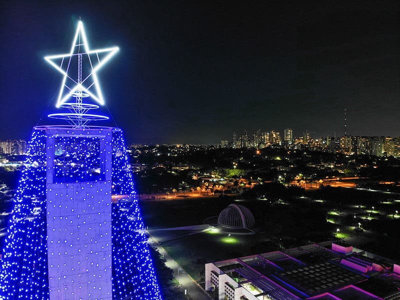 Estrela no alto da árvore de natal gigante. Ao fundo, a cidade de São Paulo vista à noite.