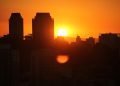 Sol nasce atrás dos prédios de São paulo. Reflexo do sol deixa o céu todo em cor laranja.
