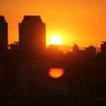 Sol nasce atrás dos prédios de São paulo. Reflexo do sol deixa o céu todo em cor laranja.