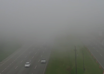 Foto mostra carros saindo do meio da neblina e fumaça impedindo visibilidade mais distante, cobrindo as duas pistas.