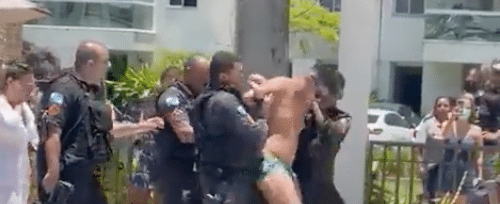 Vereador Renato Oliveira, de sunga, é carregado por policiais militares enquanto outras pessoas na piscina batem palmas.