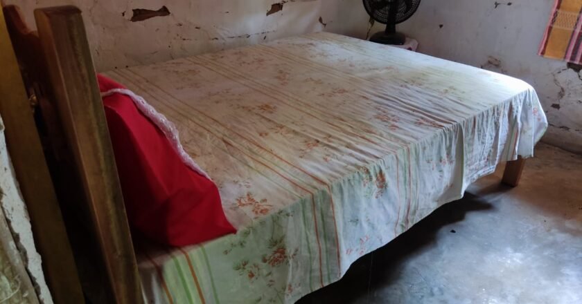 Foto mostra quarto em que a criança foi morta. O cômodo tem um ventilador giratório perto da parede, uma cama de casal, onde mãe e filho se esconderam dos criminosos.