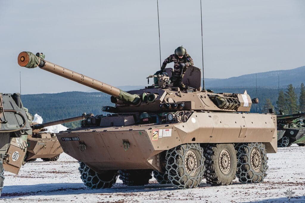Tanque de guerra no meio de campo com chão coberto de neve. Militares dentro do tanque de guerra.