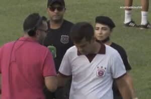 Técnico Rafael Soriano deixa o gramado acompanhado por dois seguranças e fala ao repórter, que estava ao vivo, usando fone de ouvido.