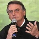 Jair Bolsonaro discursa segurando microfone com a mão direita e com a mão esquerda gesticula.