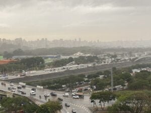 Céu encoberto e chuva fraca na região da Marginal Tietê, em São Paulo. Imagem do alto mostra região, com carros passando na marginal e também sobre a ponte da casa verde.