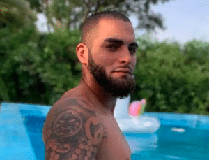 Filipi Daniel Cassiano aparece em foto sem camisa, diante de uma piscina. Ele tem barba e tatuagem em um dos braços.