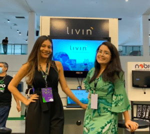 Synde Libório e Luana Rosas, da Livin, aparecem diante de um totem da empresa durante evento.