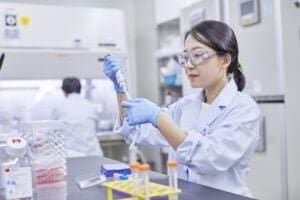 Médica geneticista da farmacêutica JCR manipula um tubo de ensaio dentro de um laboratório no Japão.