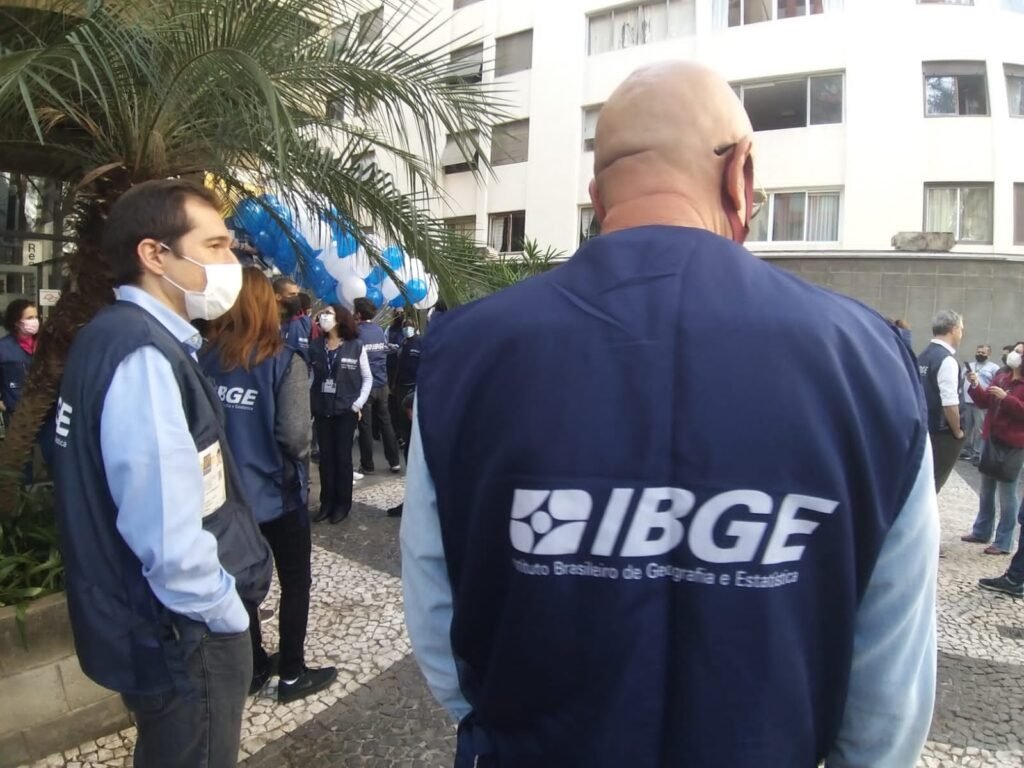 Funcionários do IBGE durante lançamento da pesquisa em São paulo. De costas para foto, um dos homens acompanha ação. Nas costas é possível ler IBGE.