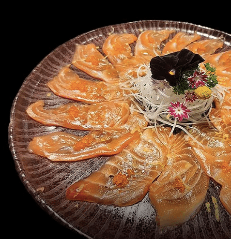 Foto do prato preparado no restaurante Masao, em Valinhos, mostra as peças organizadas em um prato redondo, com flores delicadas e pequenas ao meio.